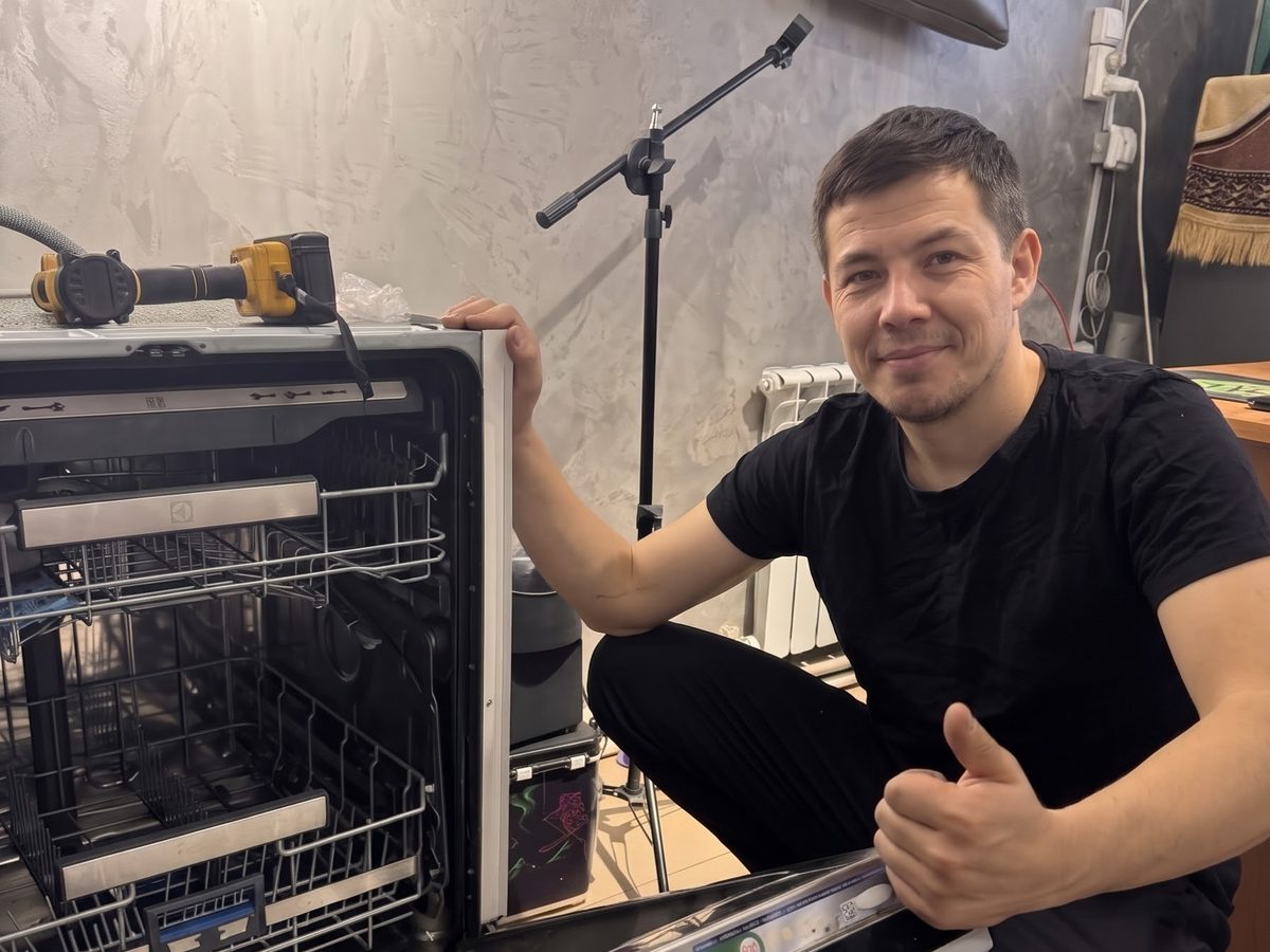 Мастер ремонтирует встроенную посудомоечную машину